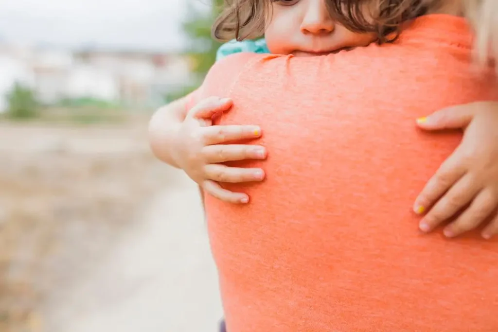 Close-up of a young child hugging a parent, representing child support and parental care.