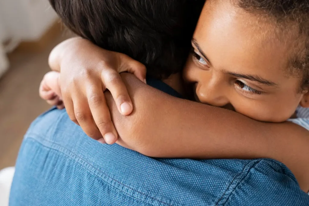 Close-up of a child hugging a parent tightly, expressing comfort, trust, and emotional support within the family.