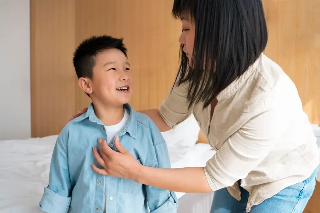 Parent helping a child get dressed while speaking gently, showing daily caregiving and attentive parenting at home.