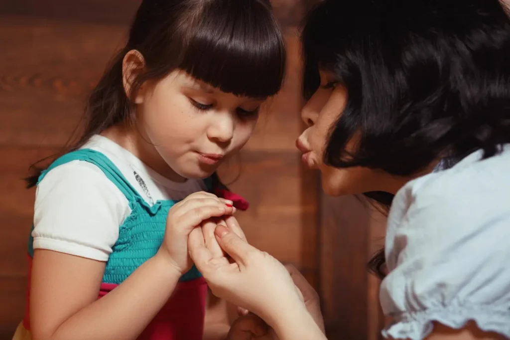 Parent gently holding a child’s hand while speaking softly, showing reassurance, care, and close parent-child connection.