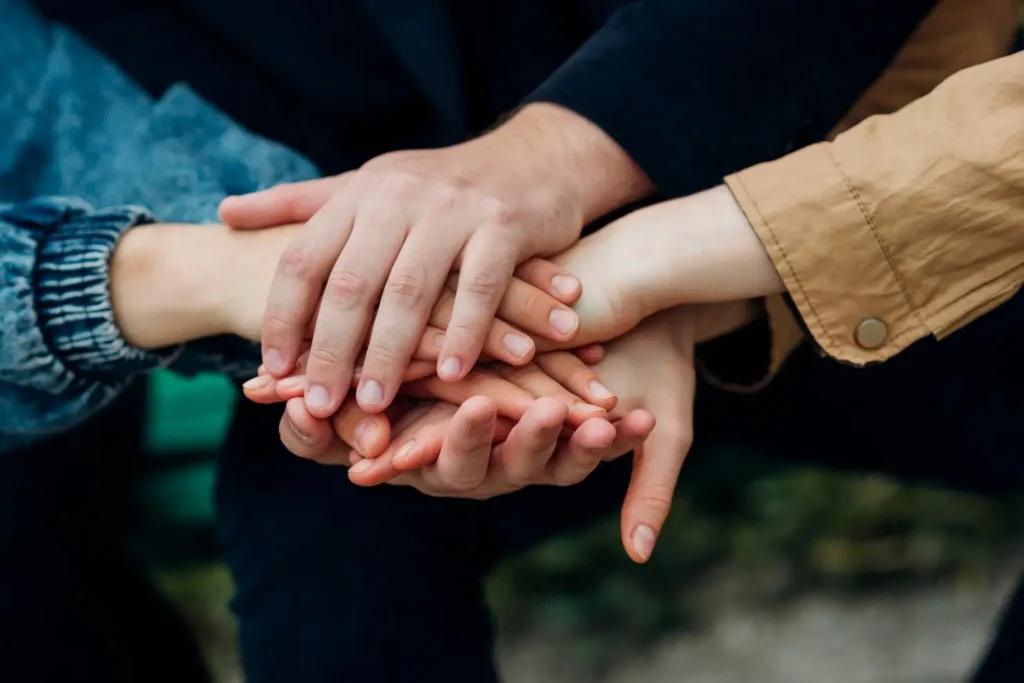 Close-up of parents and children placing their hands together, symbolizing unity, cooperation, and shared family support.