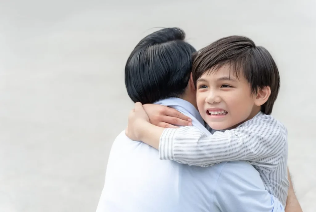 Smiling child hugging a parent, expressing comfort, love, and a strong parent-child bond.