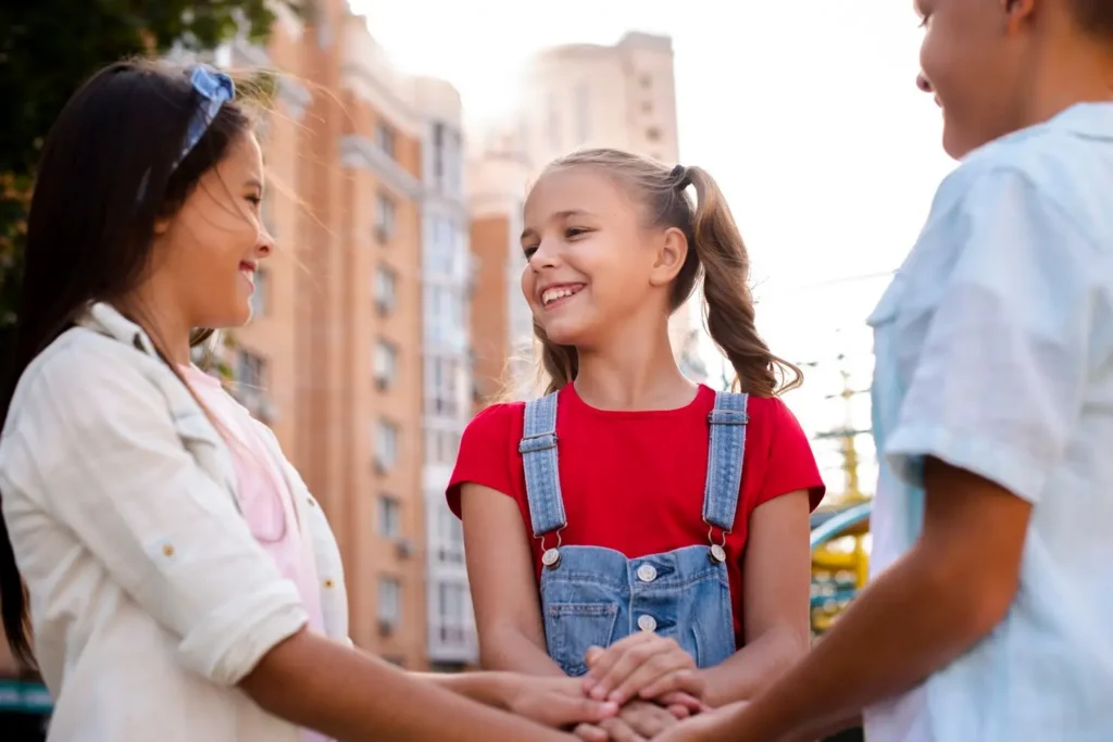 Smiling child standing between two parents outdoors while holding hands, representing co-parenting, cooperation, and the stability that consistent child support provides for a child’s future.