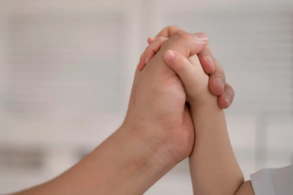 Close-up of a parent and child holding hands, symbolizing trust, guidance, and the consistent financial support that child support provides to help ensure a child’s stability and care.