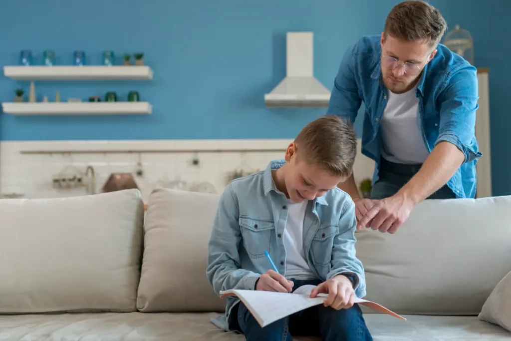 Father helping son with homework on couch during child support parenting time