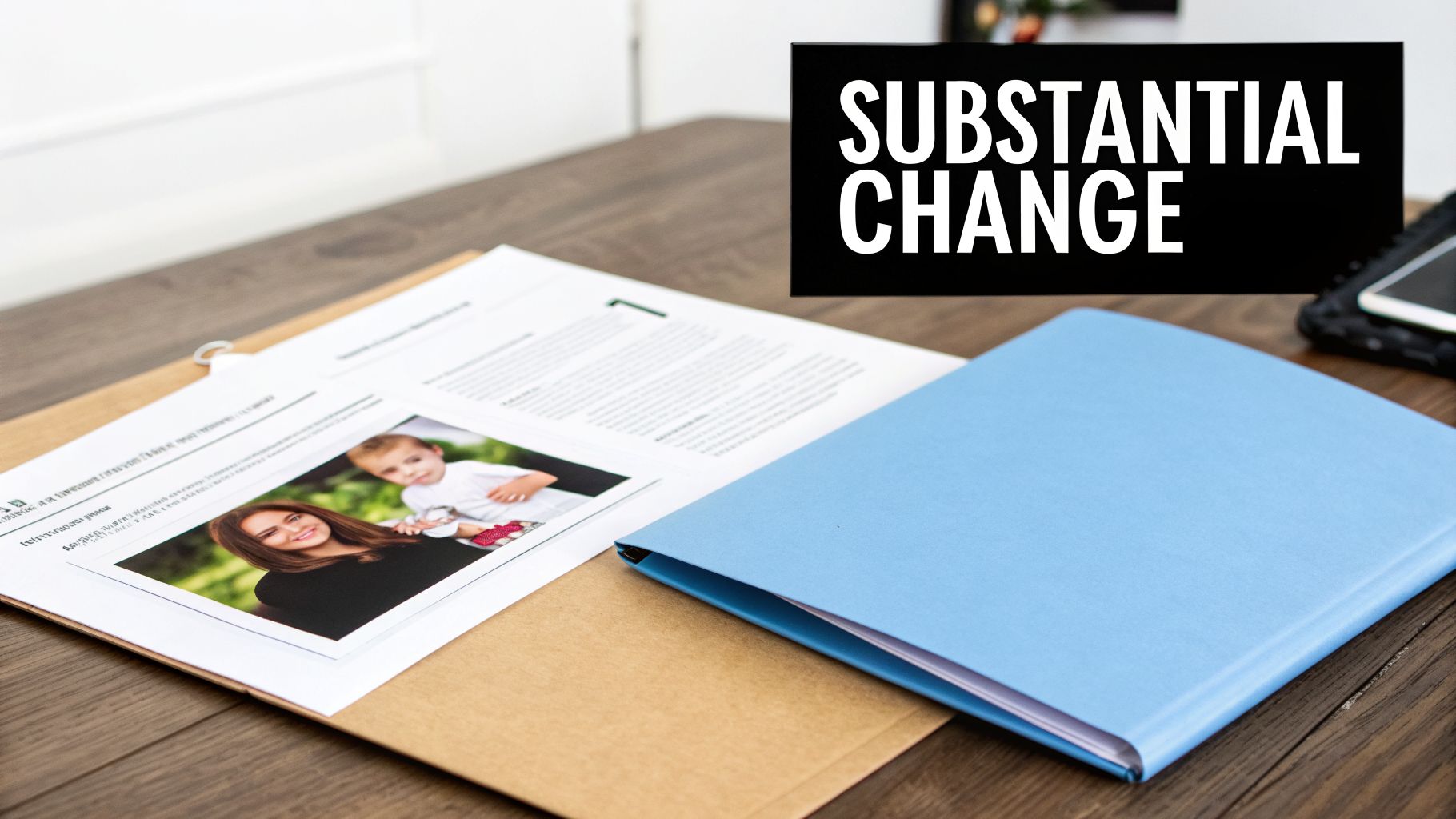 Documents, a blue folder, and a photo of a mother and child on a desk with 'SUBSTANTANTIAL CHANGE' text.